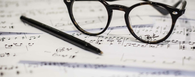 eyeglasses and a ball-point pen resting on sheet music