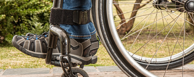 detail of person's feet and ankles in sneakers and jeans, resting on a wheelchair footrest