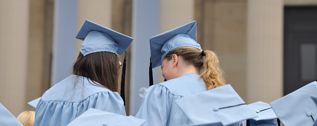 two long-haired students in graduation garb, seen from behind, at Columbia University's commencement