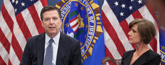 James Comey and Sally Yates seated in front of two American flags and one flag with the Justice Department seal