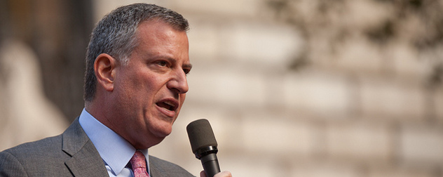 Bill de Blasio speaking outdoors with a hand-held microphone