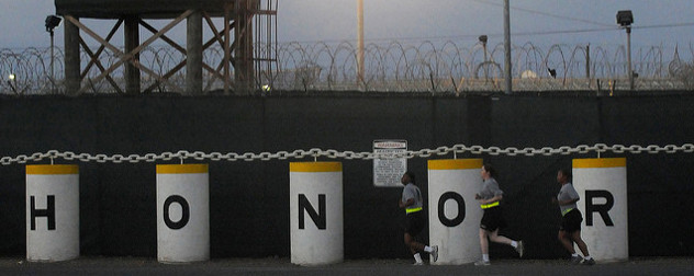 3 members of the U.S. Army run in front of the Honor Bound sign at Guantanamo's Camp Delta