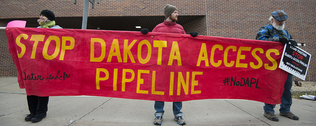 three protesters hold a banner that reads Stop Dakota Access Pipeline, Water is Life, #NoDAPL