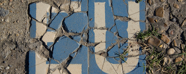 cracked sign with the white letters EU on a blue background