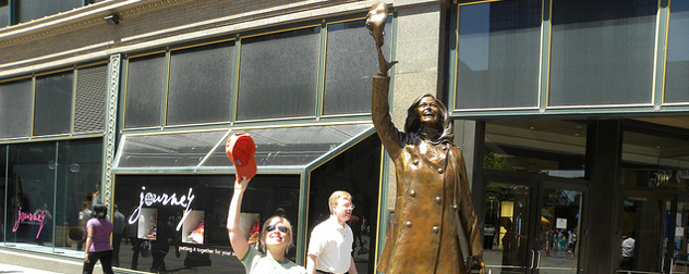 tourist tossing a baseball cap into the air next to the statue of Mary Richards in Minneapolis