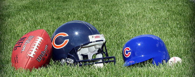 a football, a Chicago Bears helmet, a Chicago Cubs batting helmet, and a baseball resting on grass