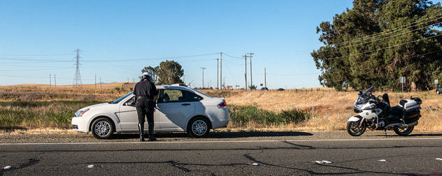 highway patrolmen speaking to a motorist in their vehicle on the shoulder