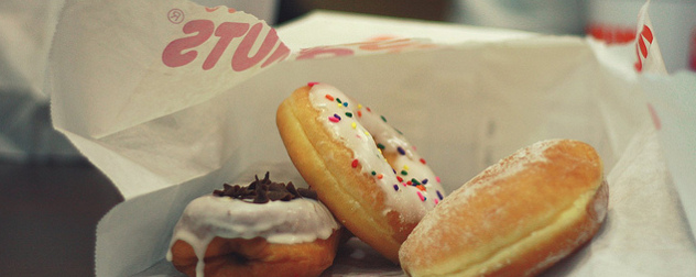 three donuts on a torn Dunkin' Donuts bag