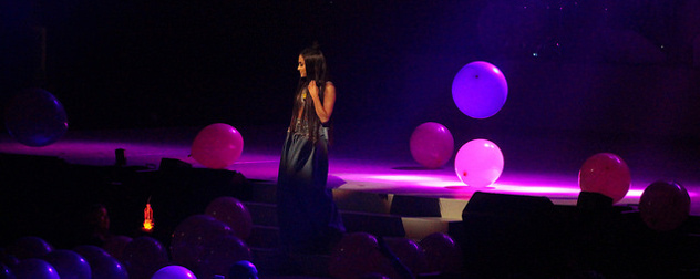 Ariana Grande on stage with large balloons falling around her