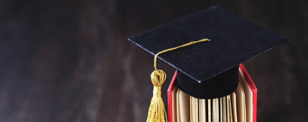 small mortarboard resting on the pages of a partly opened hardback book