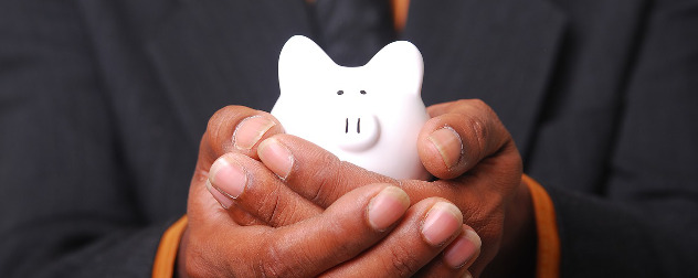 small, white piggy bank being cupped in a person's hands