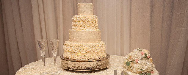 white wedding cake on a table with two champagne flutes