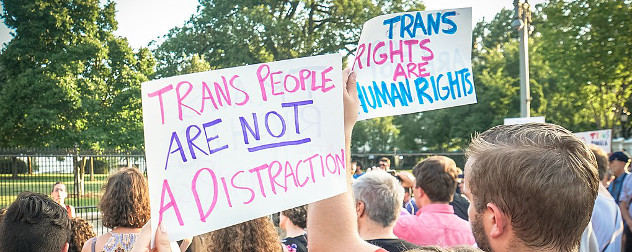 protest signs reading 'Trans People Are Not A Distraction' and 'Trans Rights Are Human Rights'