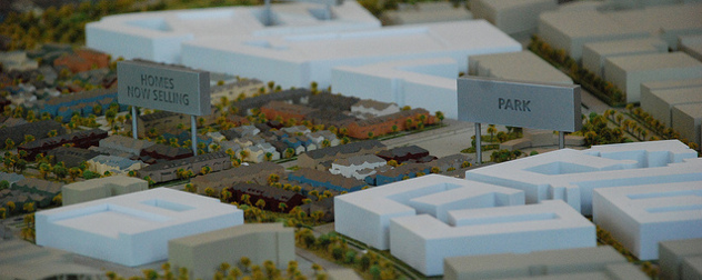 miniature neighborhood model with signs reading 'Park' and 'Homes Now Selling'