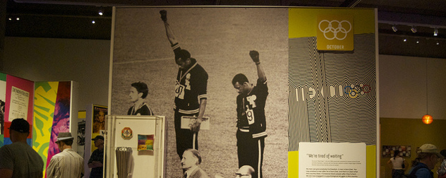 museum display featuring Tommie Smith and John Carlos raising their fists at the 1968 Olympic Games