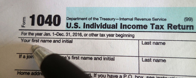 pen poised over a blank IRS Form 1040 for 2016