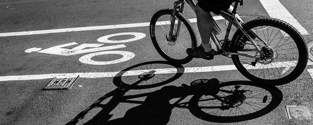 black and white image of a bike lane, with a bike rider and their shadow