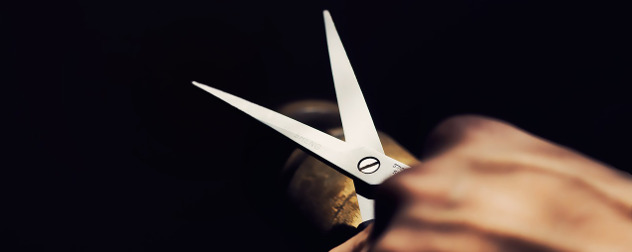 hand holding a pair of scissors against a black background