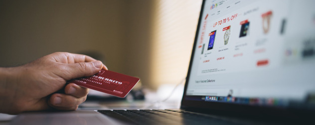 hand holding credit card in front of laptop displaying eBay shopping screen