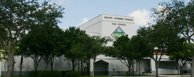 front facade of Marjory Stoneman Douglas High School, partly covered with trees