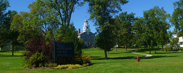 Middlebury College sign with building visible through tress in the background