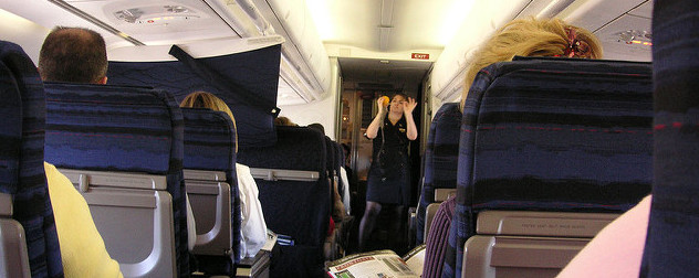 flight attendant demonstrating how to tighten a passenger oxygen mask