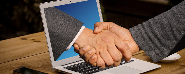 image of hands shaking, one emerging from a laptop monitor