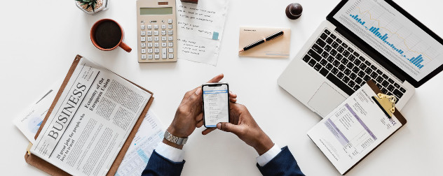 overhead view of man holding smartphone and surrounded by business accessories