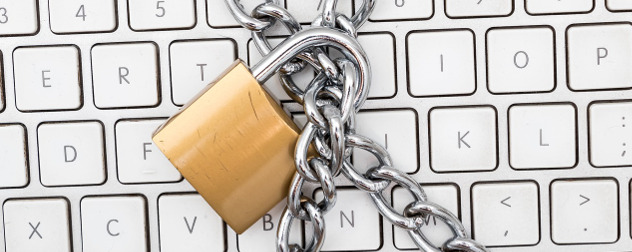 brass padlock and chains on computer keyboard representing cybersecurity
