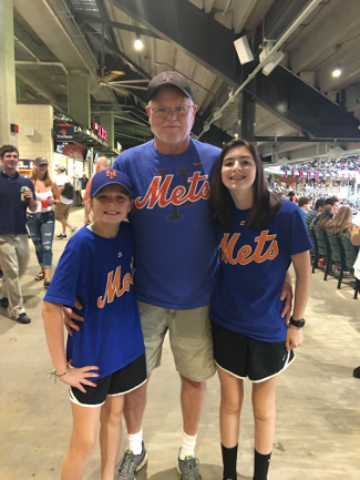 three fans in Mets gear at a game