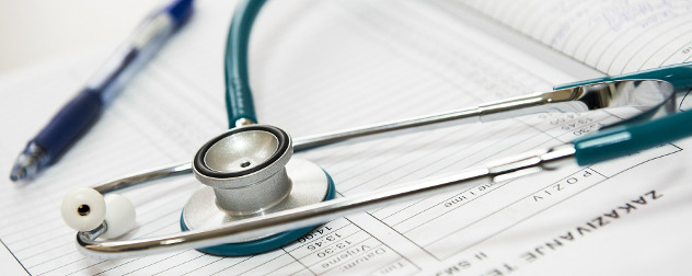 stethoscope and pen resting on top of paper medical forms