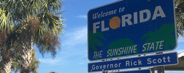 road sign reading 'Welcome to Florida, The Sunshine State' and 'Governor Rick Scott'