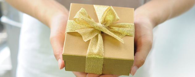 hands offering a gold gift box with a gold ribbon.