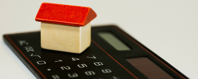 small wooden house resting on a simple calculator