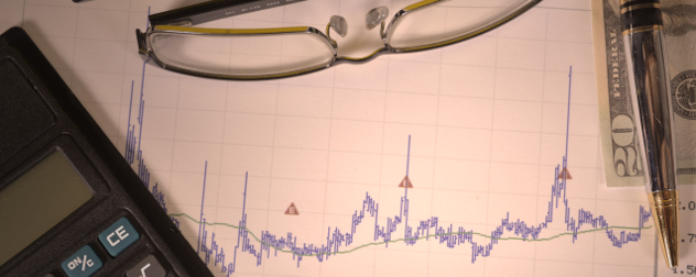 graph with calculator, glasses, 20-dollar bill and pen.