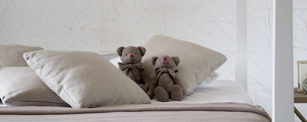 two small teddy bears on a bed.