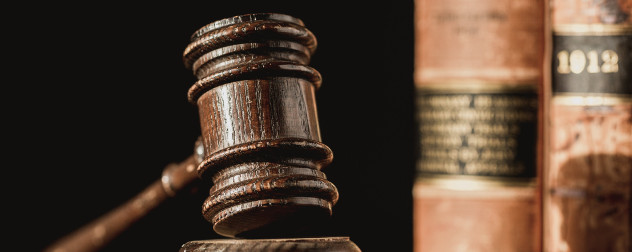 wooden judge's gavel with out-of-focus law books in background.