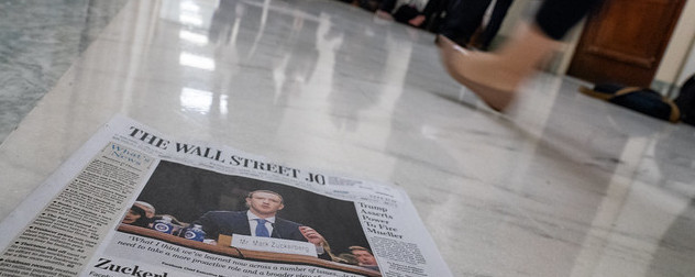 print issue of The Wall Street Journal on a marble floor, a person walking by in the background.