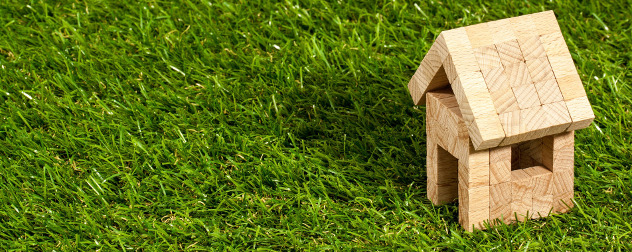 small wooden model house on grass.