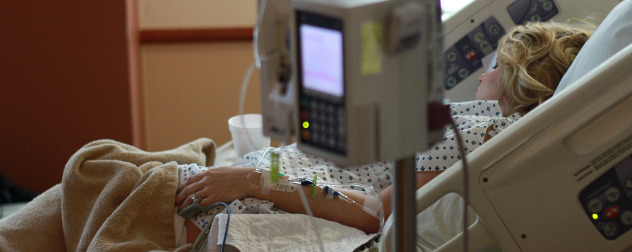 woman in hospital bed, out-of-focus monitor in foreground.