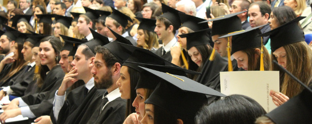 graduates with black caps and gowns, seated.