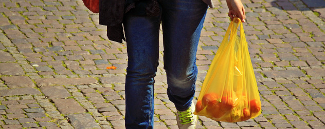 shopper carrying a plastic bag full of oranges