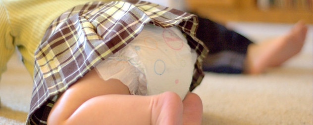 detail of crawling baby wearing a dress and a diaper.