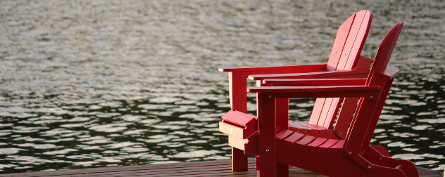 red adirondack chairs on a dock by water.