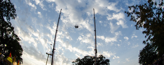 a slingshot-style ride seen against a twilight sky with trees.