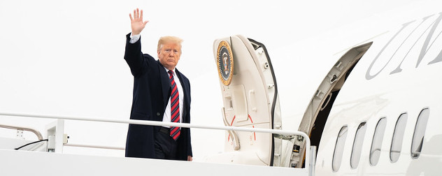 President Donald Trump boards Air Force One, waving.