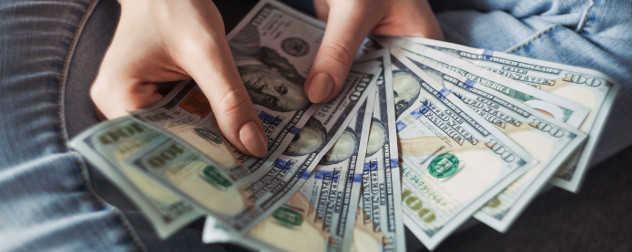 hands holding 100 US Dollar banknotes.