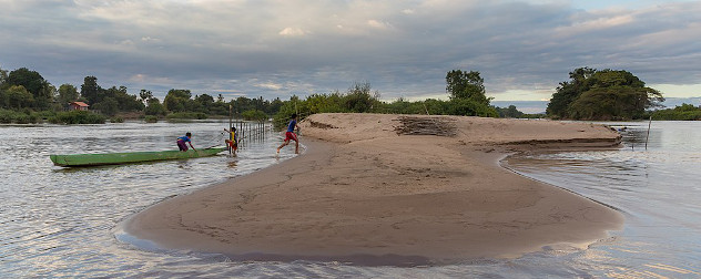 Three children running from their boat up a sand bank on the Mekong River near Si Phan Don.