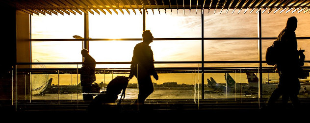 silhouette of people walking through an airport against a window.