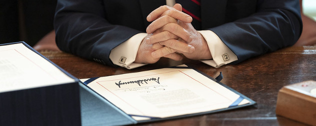 President Donald Trump's hands, folded, next to the signed version of the government's coronavirus relief law, the CARES Act.